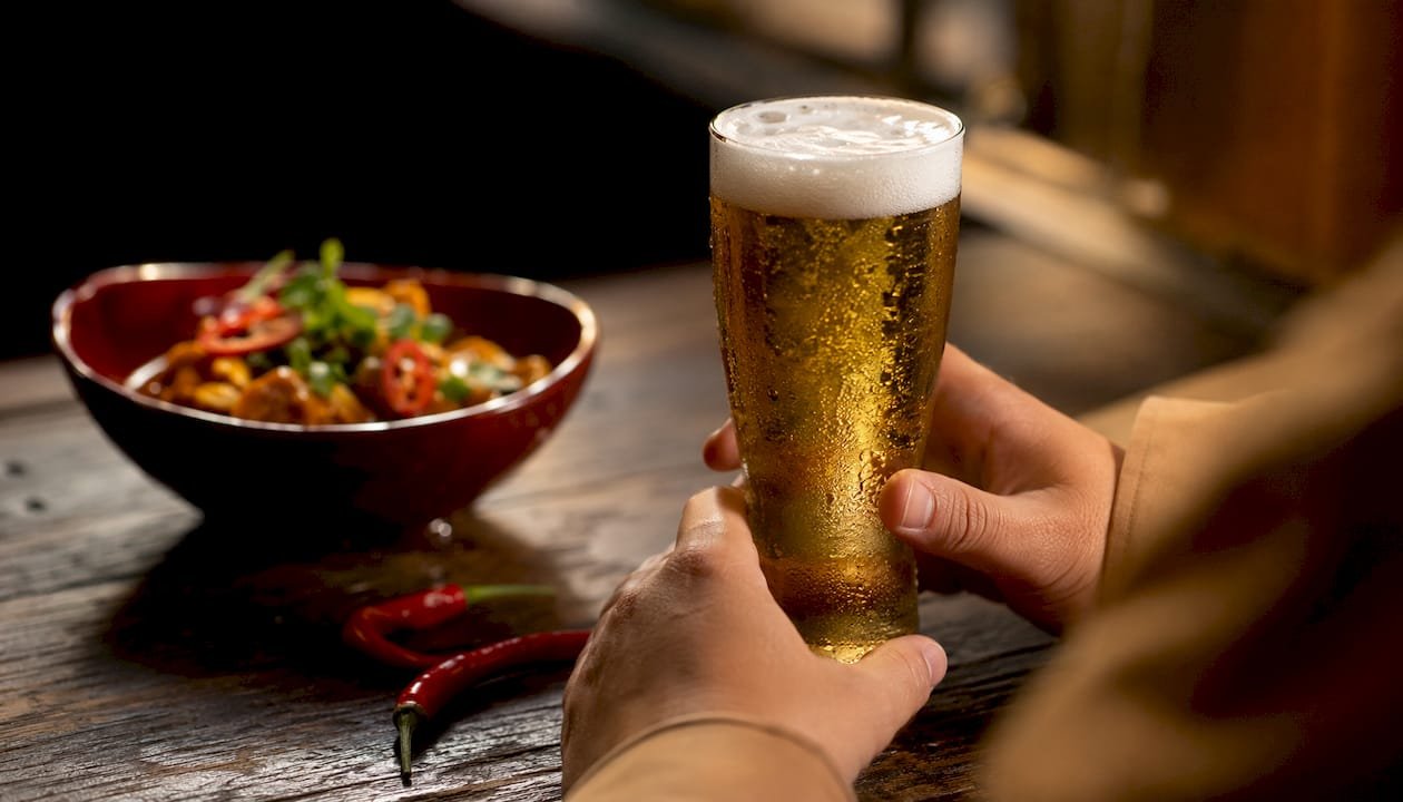 Close-up frosted beer glass near spicy curry