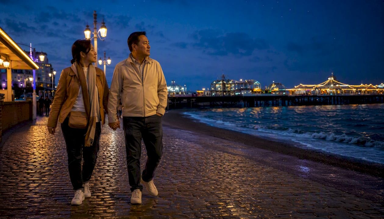 Couple walking on Brighton seafront at dusk