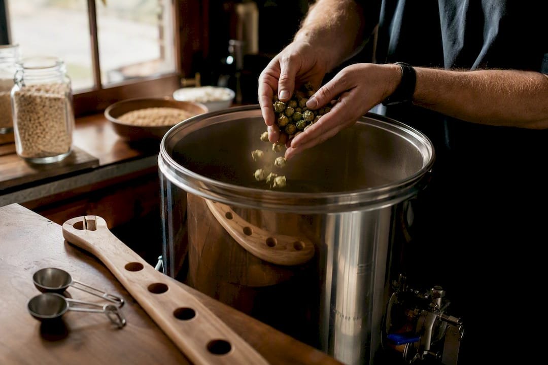 Hands adding hops to fermenter in homebrew